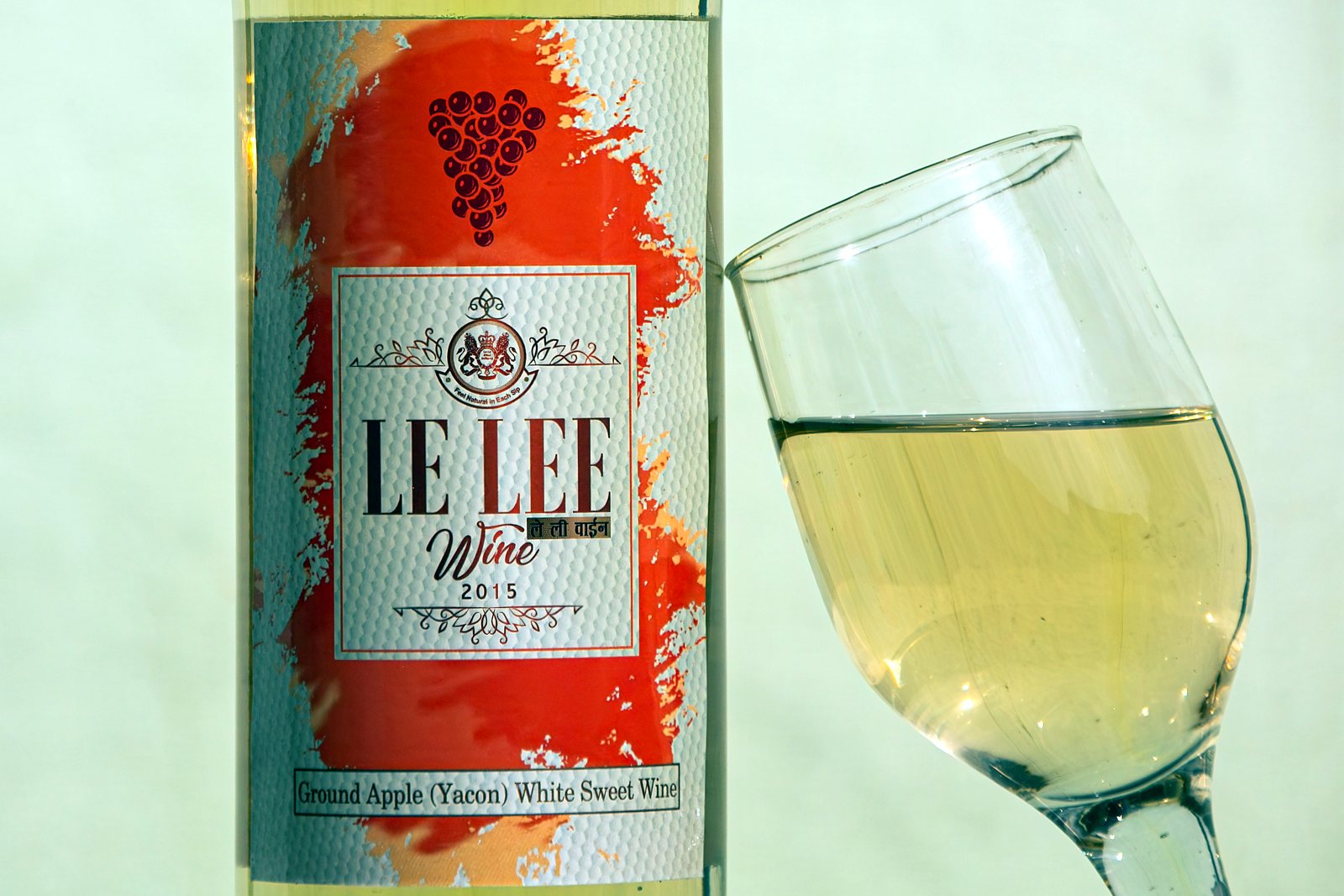 A glass of pale golden wine beside the Le Lee white label